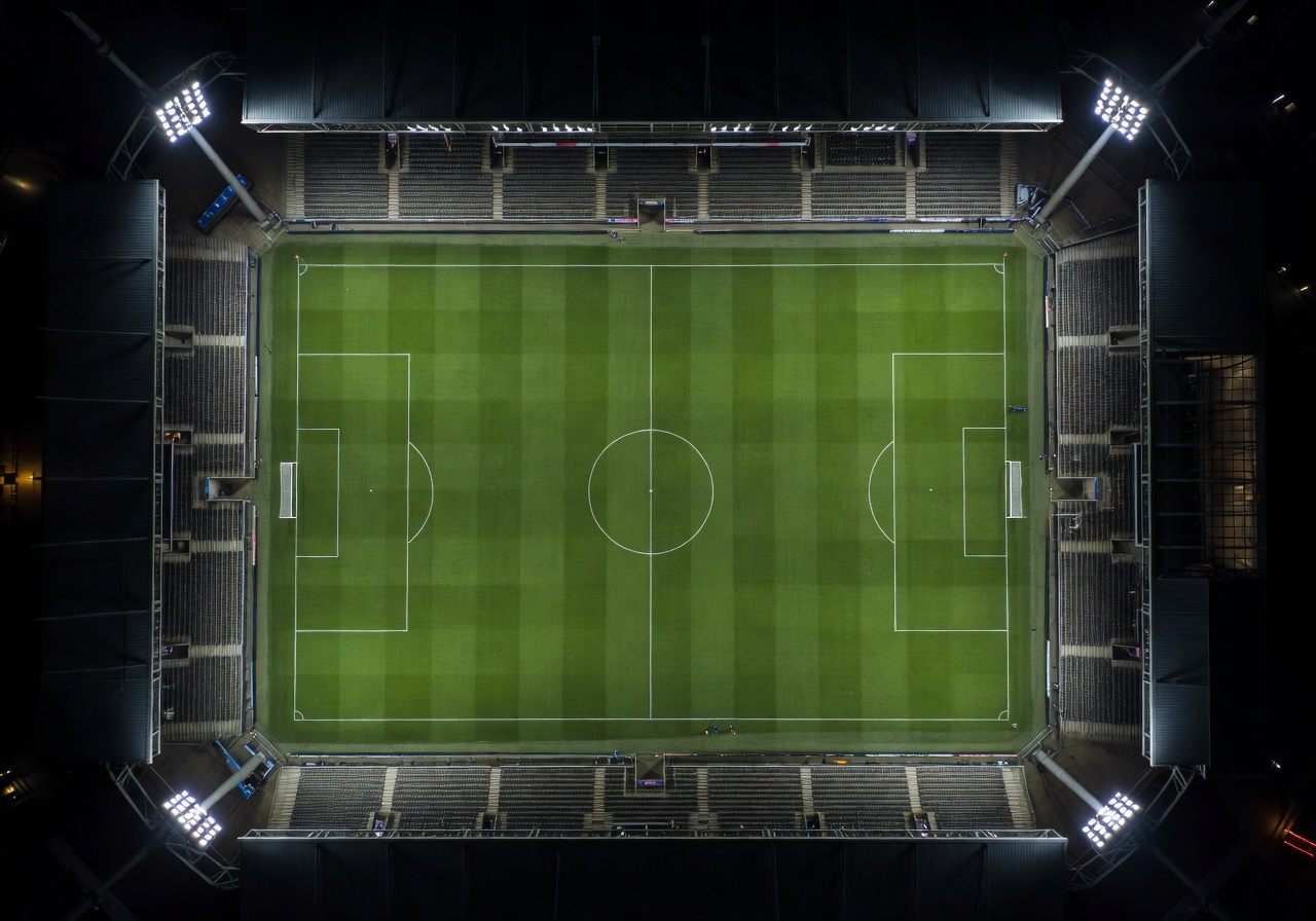 Aerial view of a floodlit football stadium pitch at night